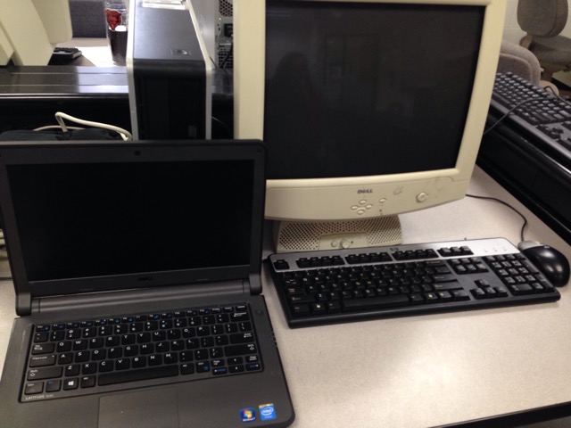 Unit 5 student laptop standing by a computer commonly found in a school computer lab.