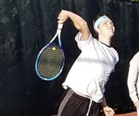 Senior, Nick Banser goes up for serve in a match from last year.