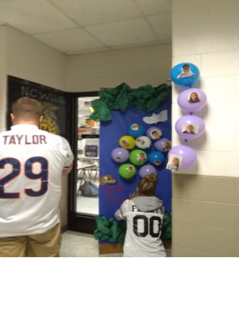 Trevor Taylor  wearing number 29, helps decorate his homeroom door in hopes to win the pizza party for his class.  The judges come around on today, 9-11-19, to pick the winner of the decorate a door competition.