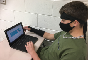 Senior Ryan Griffin works on his laptop while wearing a mask--a requirement for all students attending in-person school.