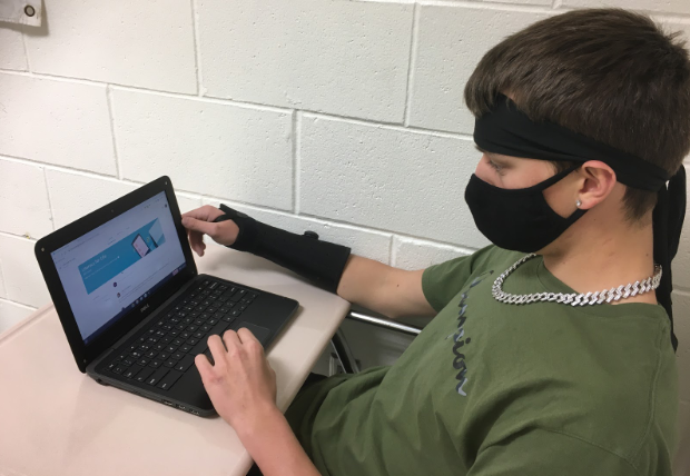 Senior+Ryan+Griffin+works+on+his+laptop+while+wearing+a+mask--a+requirement+for+all+students+attending+in-person+school.