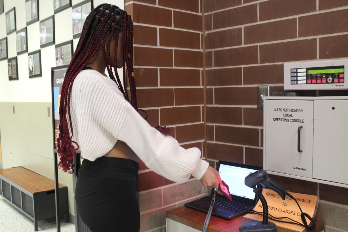 Senior Regina Aduku scans into the main office scanner during one of her blended classes. Like Aduku, students throughout Normal West are seeing a bigger emphasis on their ID usage. Dr. Codron and the rest of the Normal West administration team has begun to further emphasize the importance of ID use in their new "Plan to Scan" initiative. 
