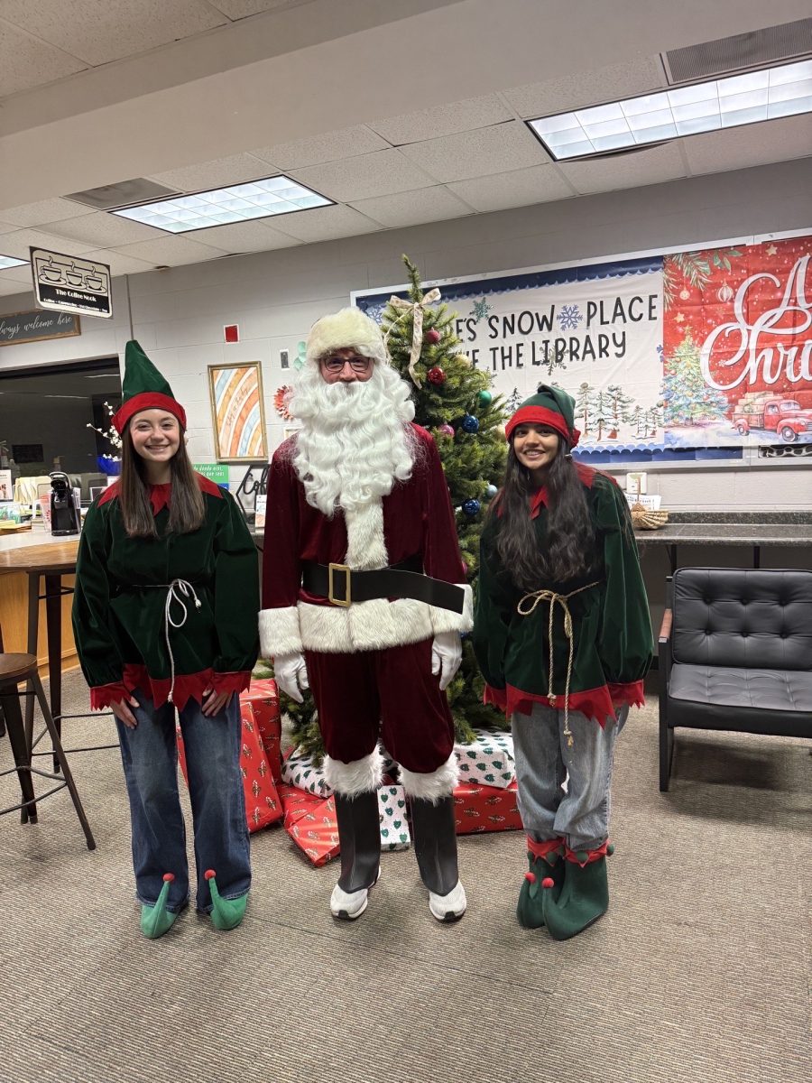 Normal West's Project Pen Pals recently organized an event that reached Unit 5 elementary schools. Above, seniors Sophie Wethington and Aashna Patel pose with Santa at the student-organized event designed to help elementary students write letters to Santa. 