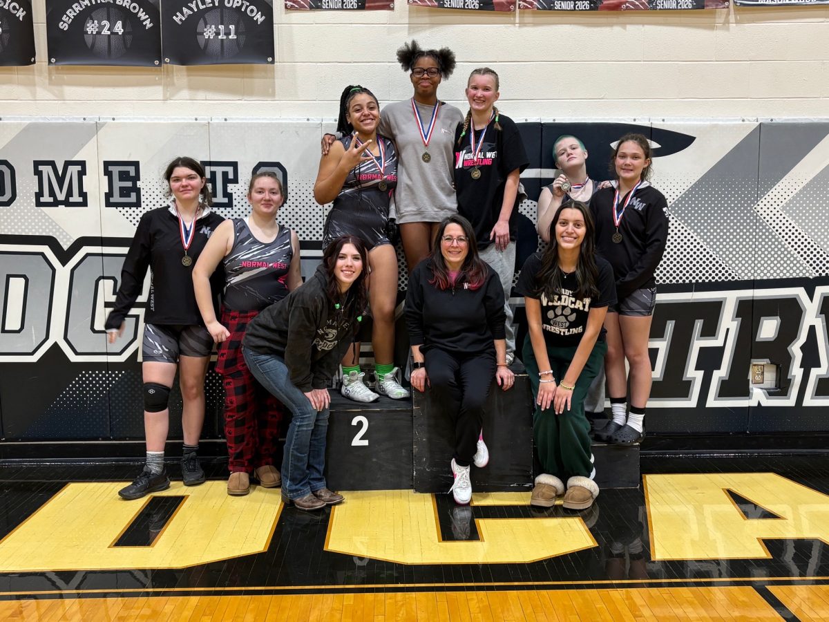 Margaret Lehr, the head coach of the Normal West girls wrestling program, has been accustomed to breaking barriers in the sport her whole career. That is why she was named the grand marshal of this year's IHSA State tournament that is bein held at Grossinger Motors Arena here in Normal. Above, Lehr poses with her current team.